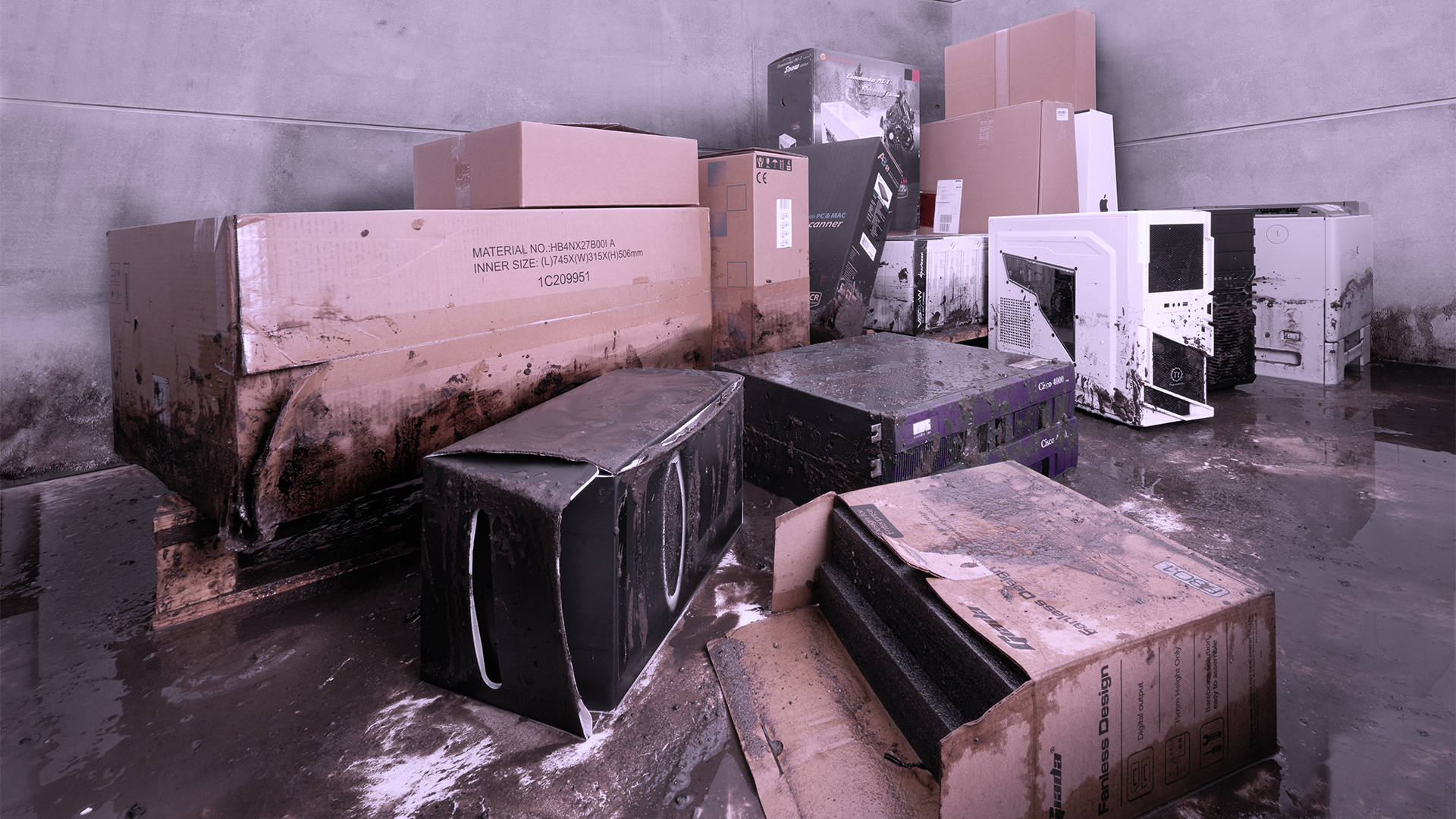 A basement room containing computers that have been soiled and damaged by backwater.