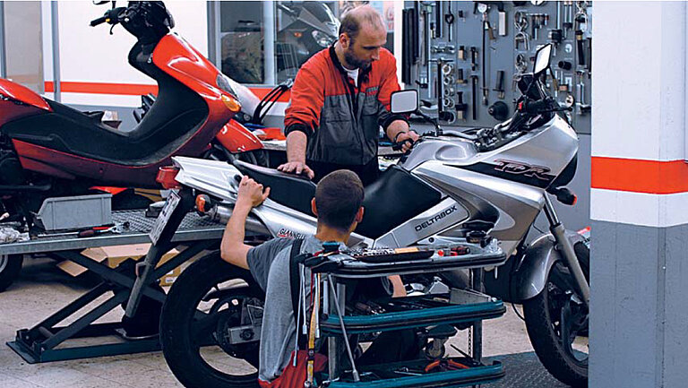 Car repair shop A picture of a workshop where two people are working on a motorbike.